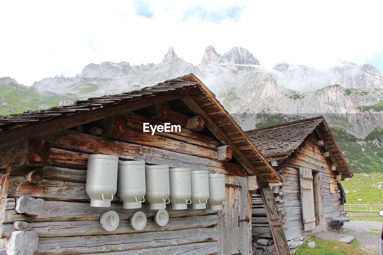 Milk canisters on wooden cottage