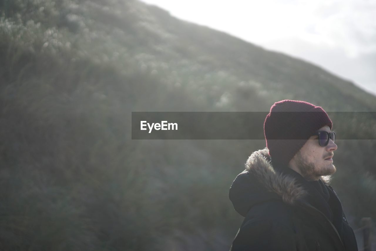 Young man looking away against mountain