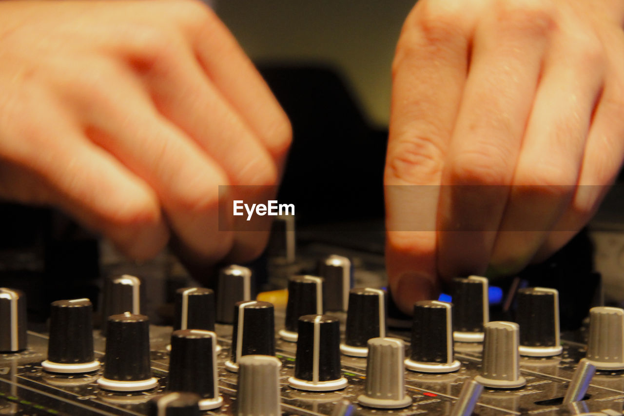 Cropped image of dj mixing with audio control equipment