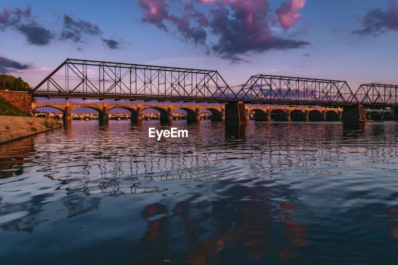Bridge over river against cloudy sky