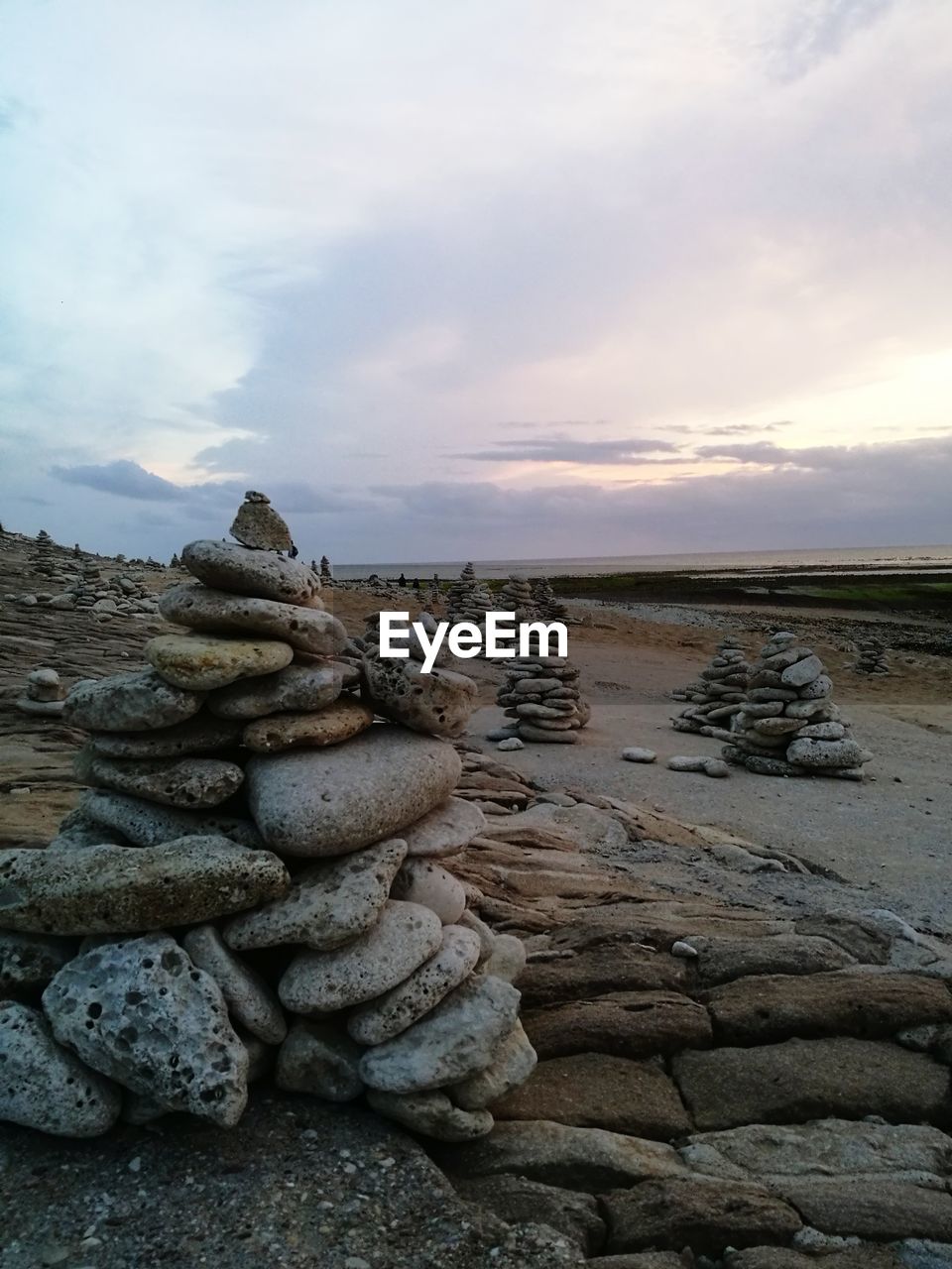 STACK OF STONES ON BEACH AGAINST SKY