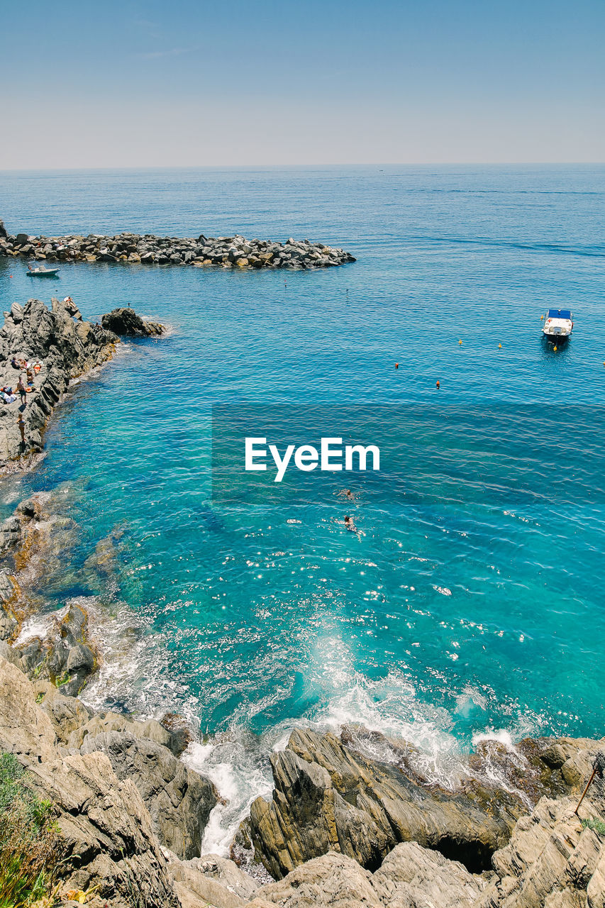 HIGH ANGLE VIEW OF ROCKS ON SEA SHORE AGAINST SKY