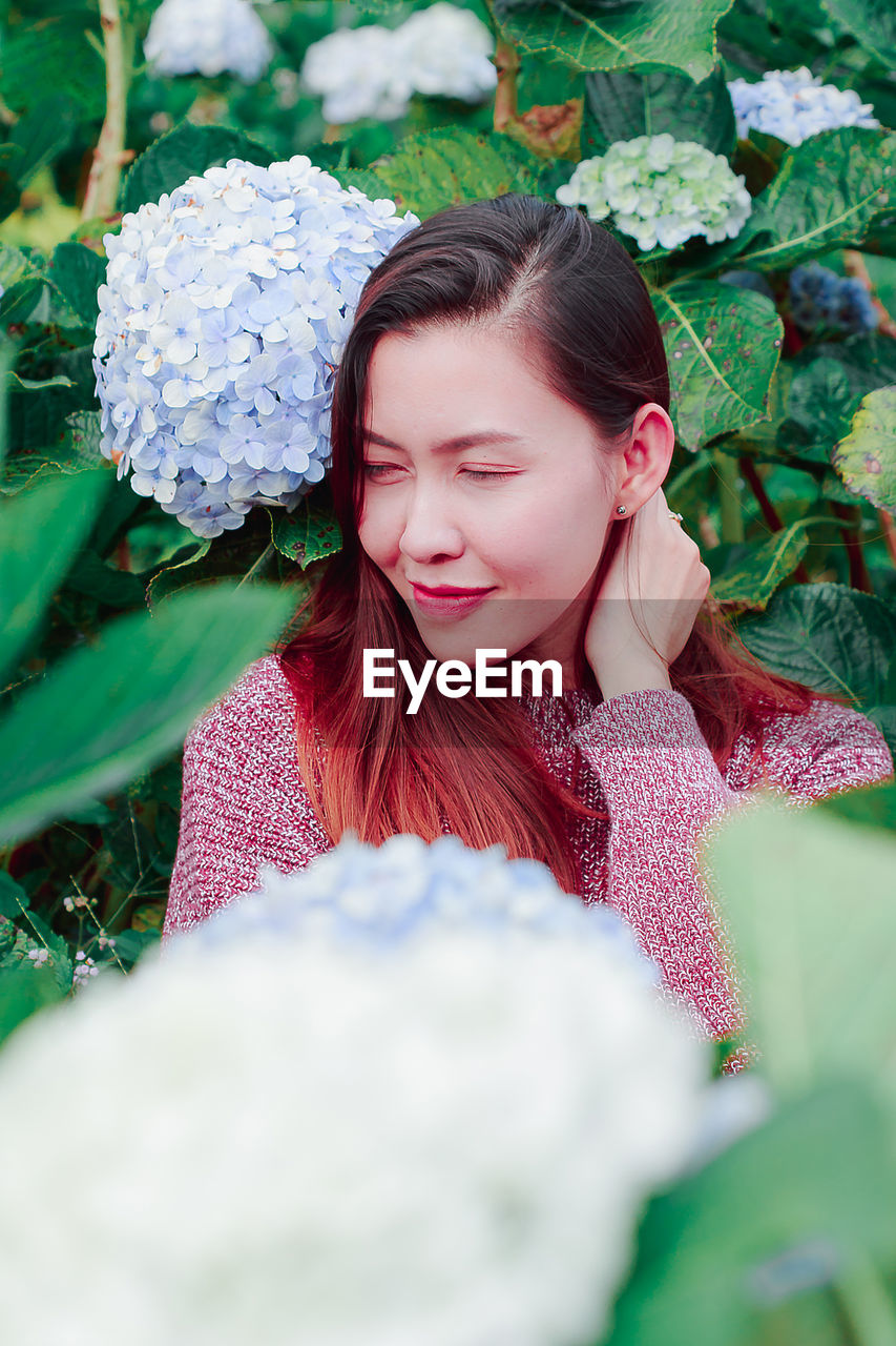 Mid adult woman by flowering plants in park