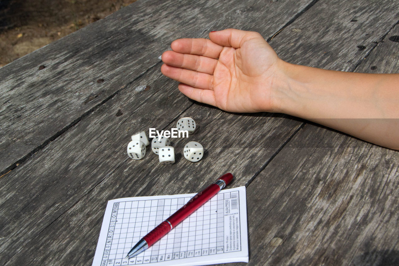 HIGH ANGLE VIEW OF HAND HOLDING WOODEN TABLE