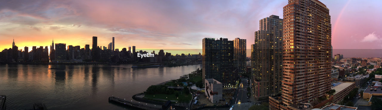 East river amidst modern buildings at manhattan during sunset