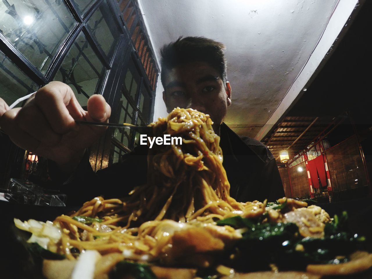 Portrait of man having noodles at restaurant