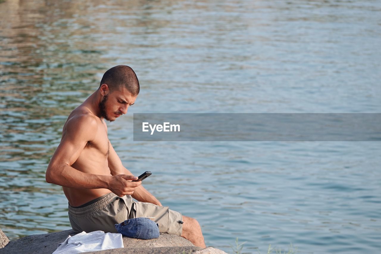 Rear view of shirtless man standing in lake