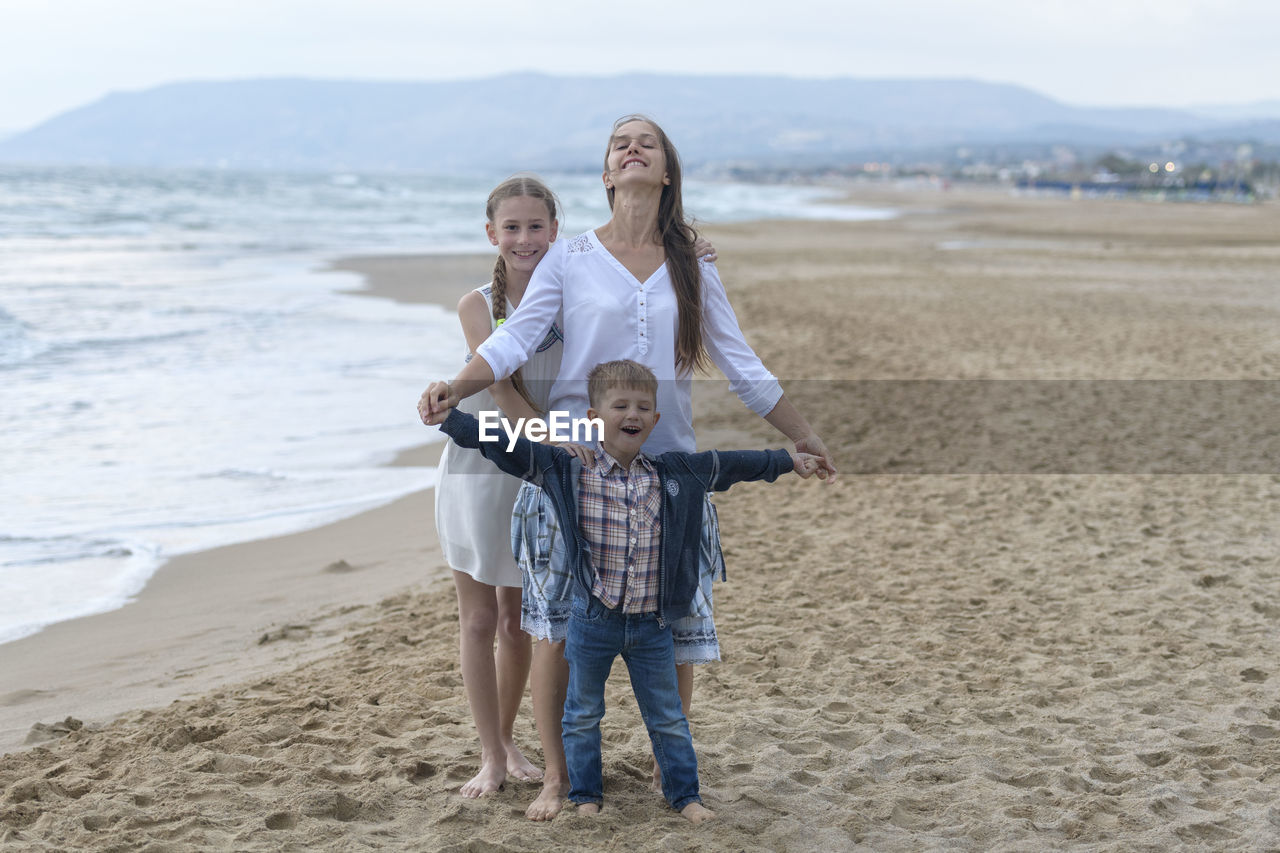Portrait of smiling mother and kids standing at beach