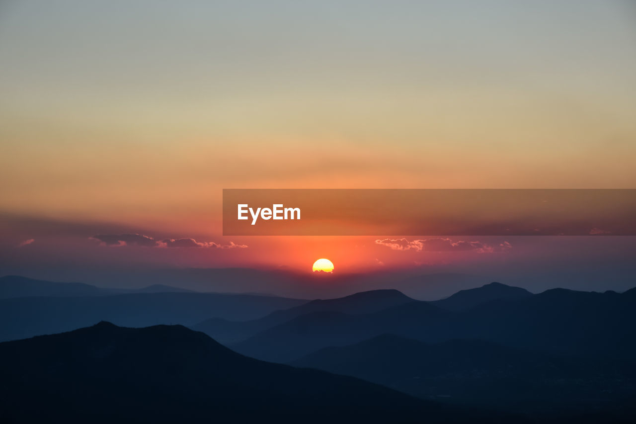SCENIC VIEW OF SILHOUETTE MOUNTAINS AGAINST SKY AT SUNSET