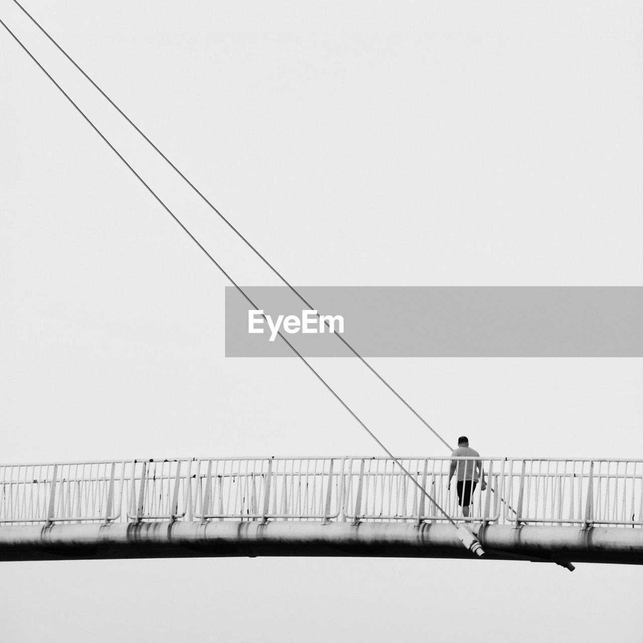 Man standing on bridge against clear sky