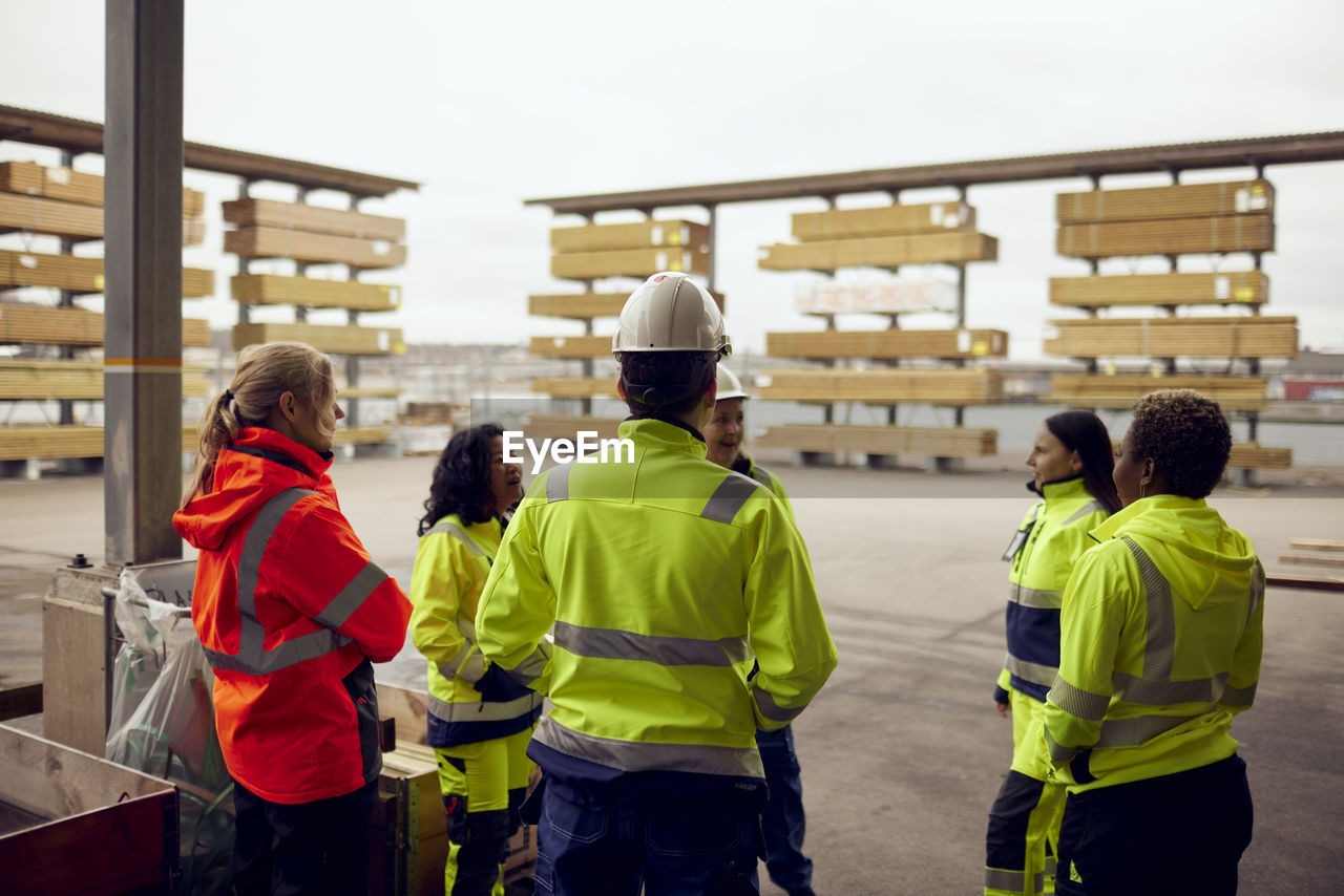 Multiracial female colleagues in reflective clothing discussing at industry