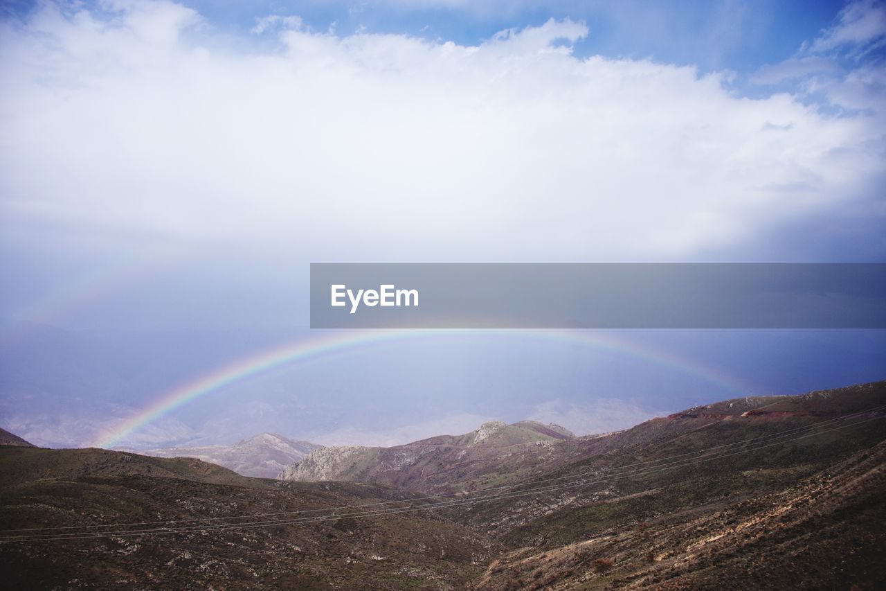 Scenic view of rainbow over mountains against sky