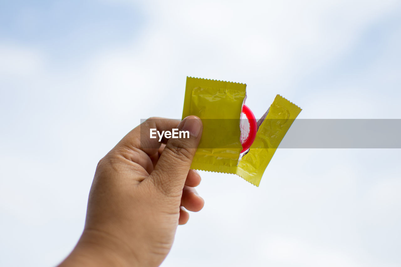 Close-up of man holding condom outdoors