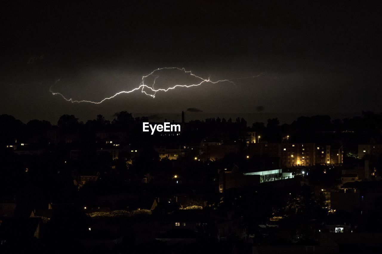 LIGHTNING OVER ILLUMINATED CITYSCAPE AGAINST SKY