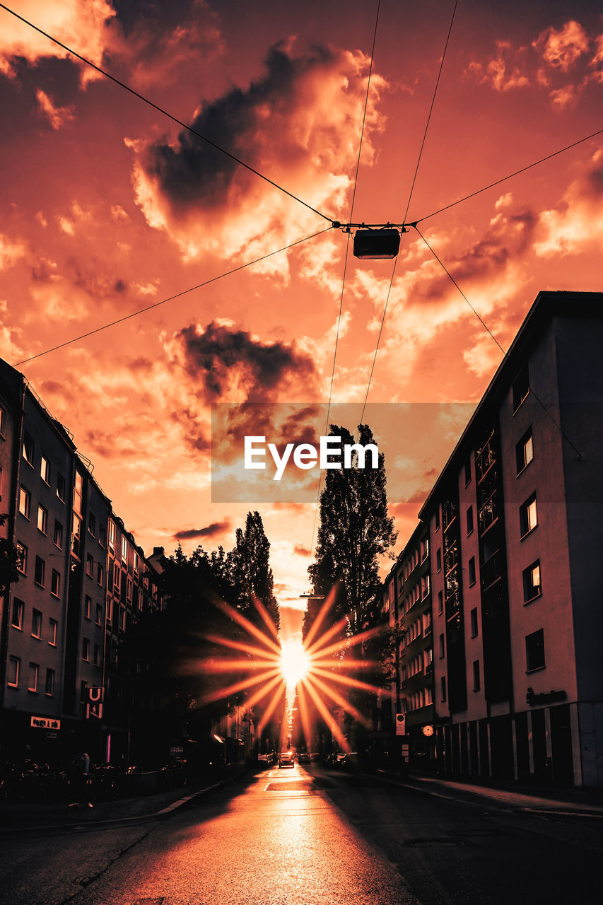 STREET BY BUILDINGS AGAINST SKY DURING SUNSET