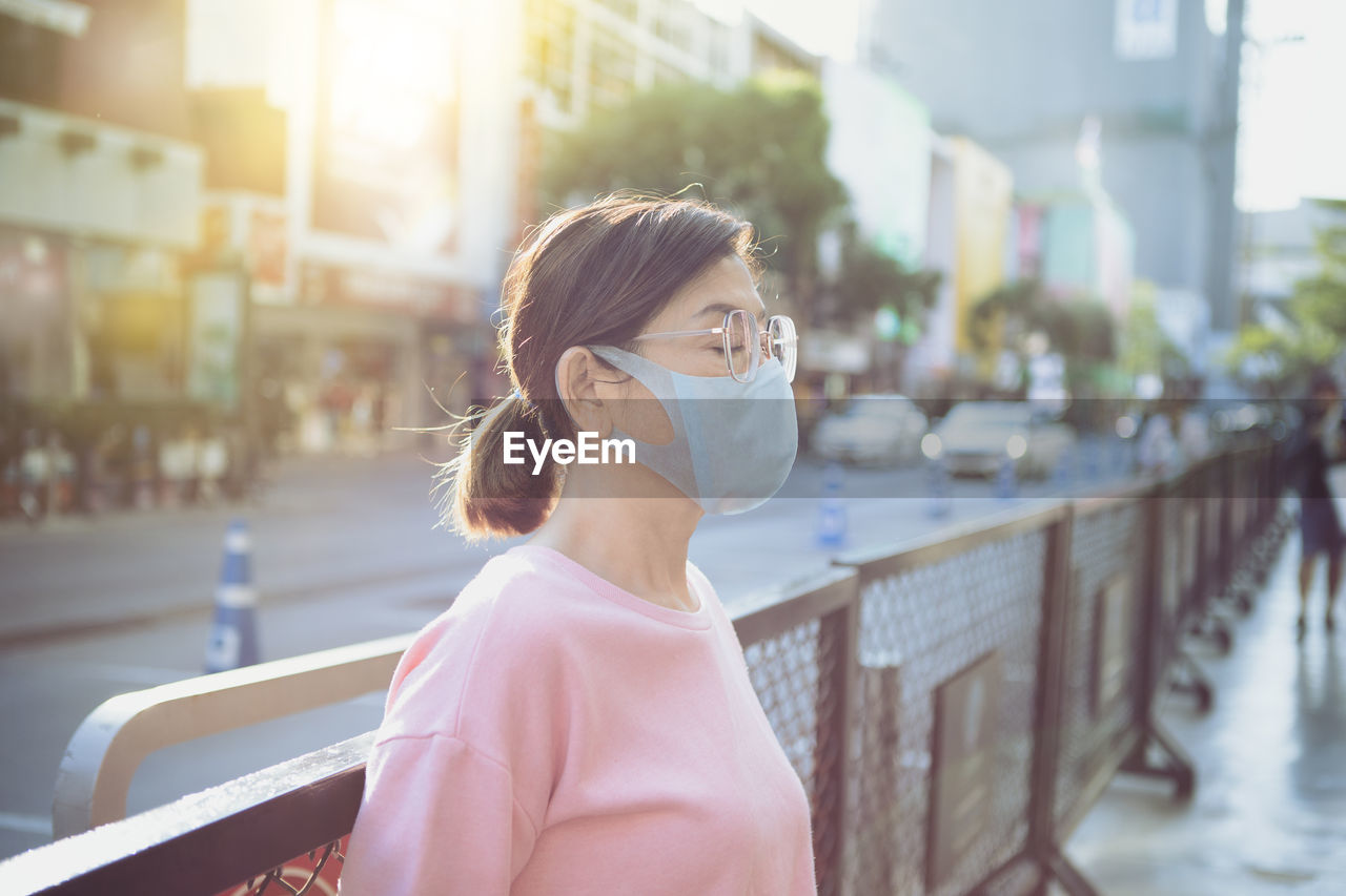 Asian woman wearing face mask standing at city street