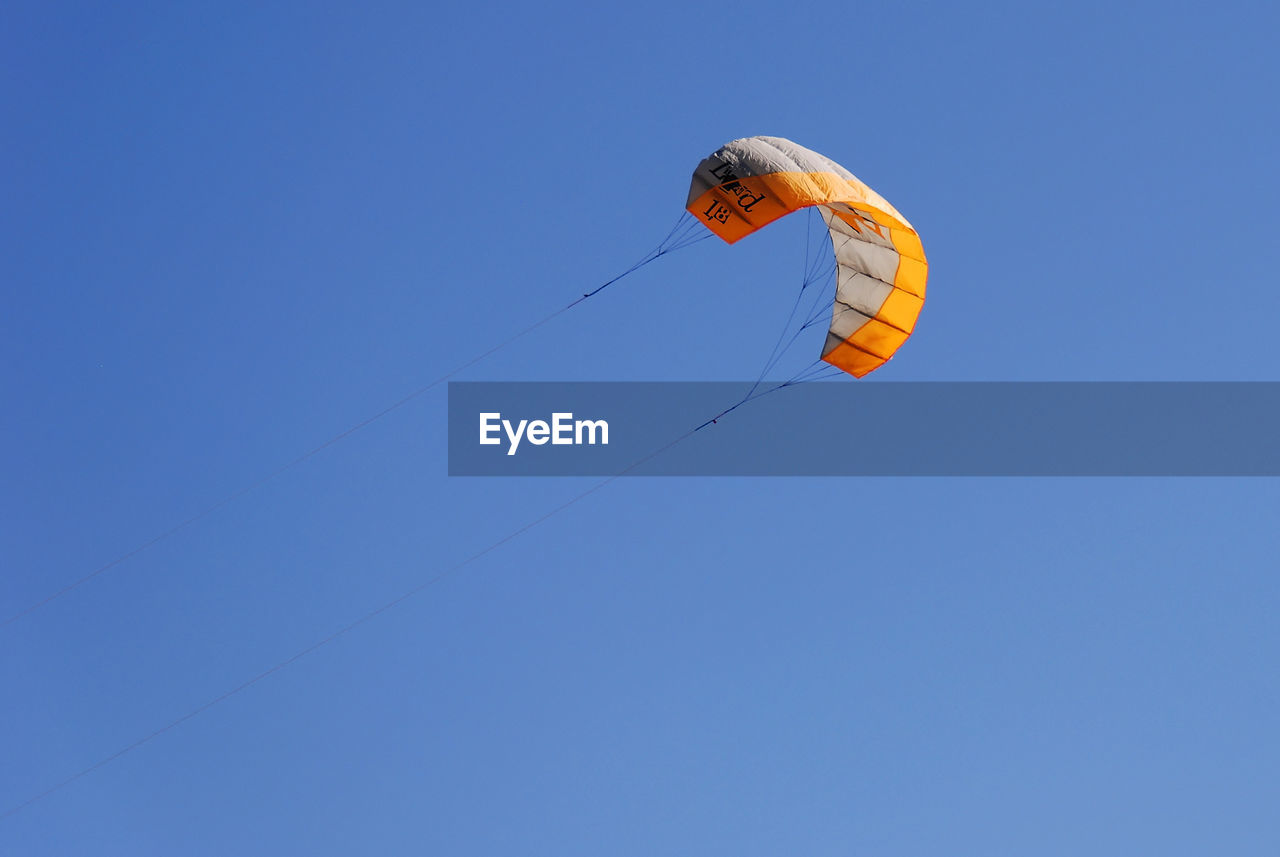 LOW ANGLE VIEW OF KITE FLYING IN CLEAR BLUE SKY
