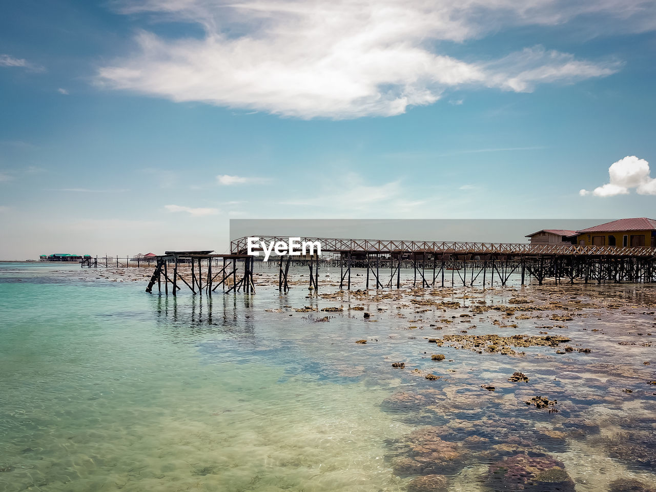 Wooden posts on coral beach by sea against sky.