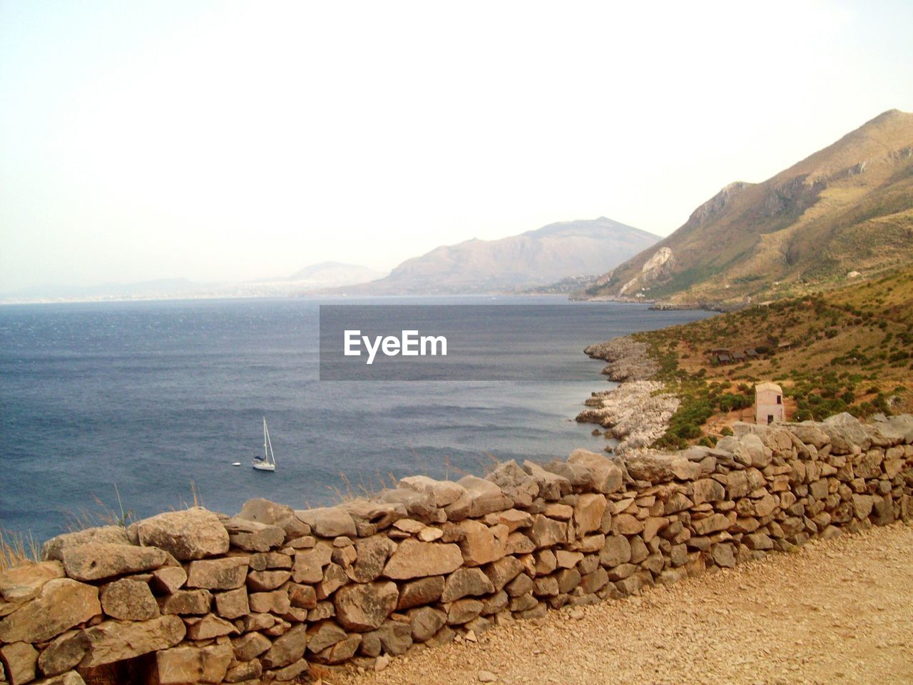 SCENIC VIEW OF SEA BY MOUNTAIN AGAINST CLEAR SKY