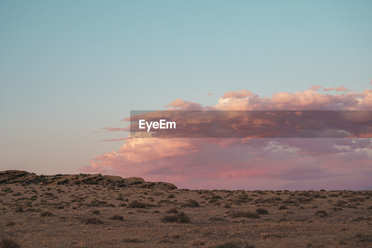 Pink clouds at sunset and desolate flat landscape, copy space for text