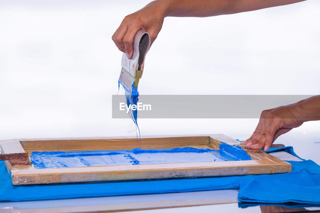 Cropped image of person screen printing against white background