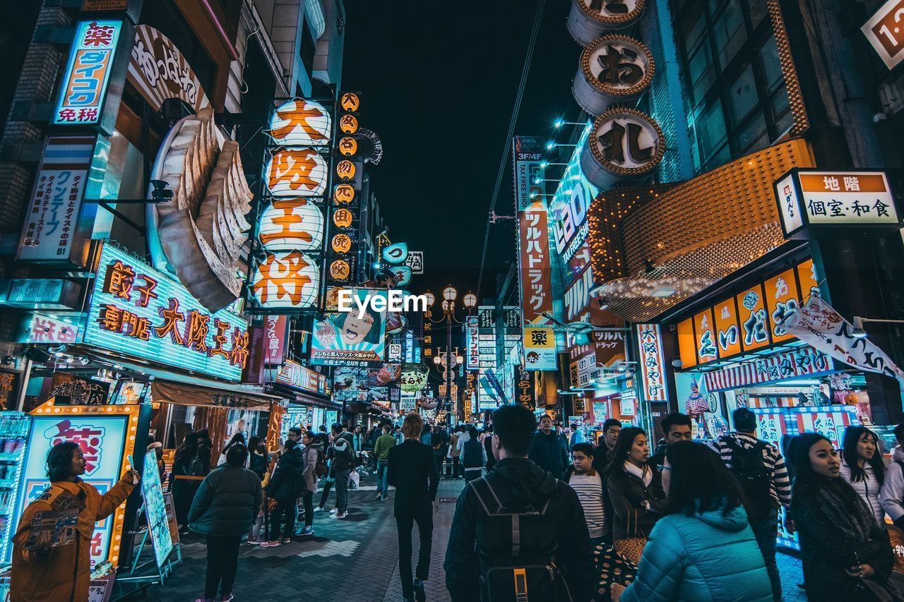 People on illuminated street at night in city