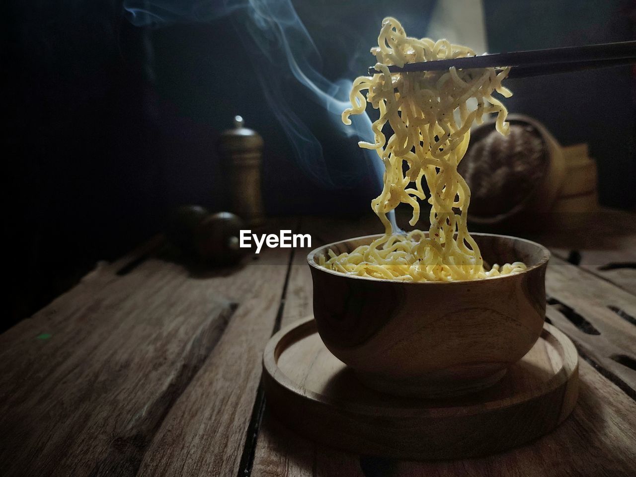 A bowl of hot boiled noodles is ready to eat in a wooden table. dark mood photography concept