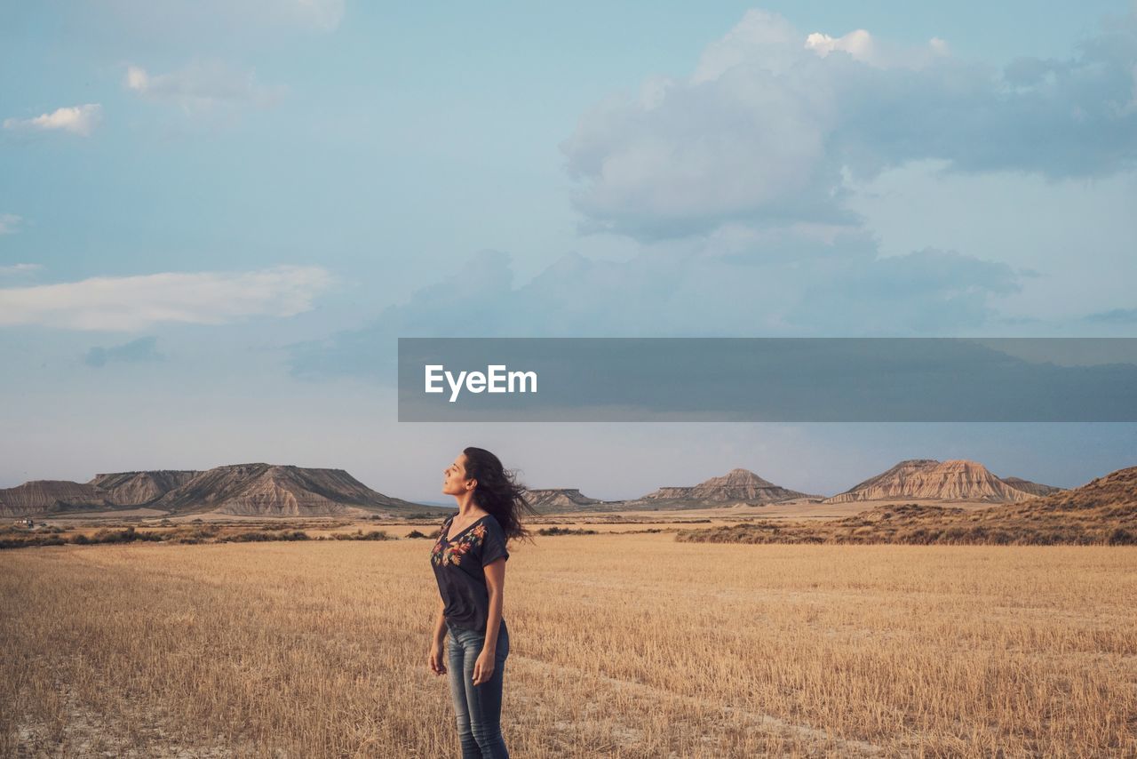 Side view of woman standing on field against sky