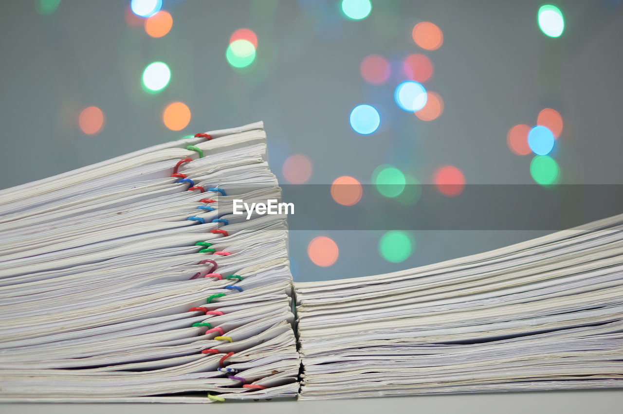 Close-up of paper stacked on table against blurred lights
