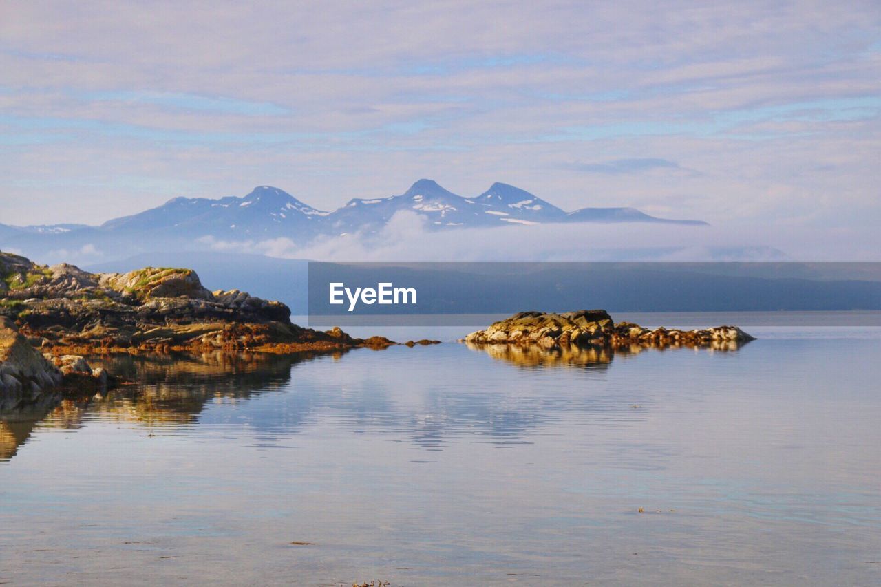 Scenic view of sea and mountains against sky