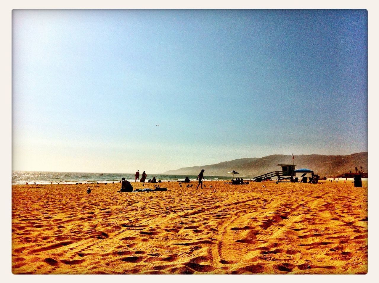 Surface level view of sand with people enjoying summer on zuma beach against clear sky