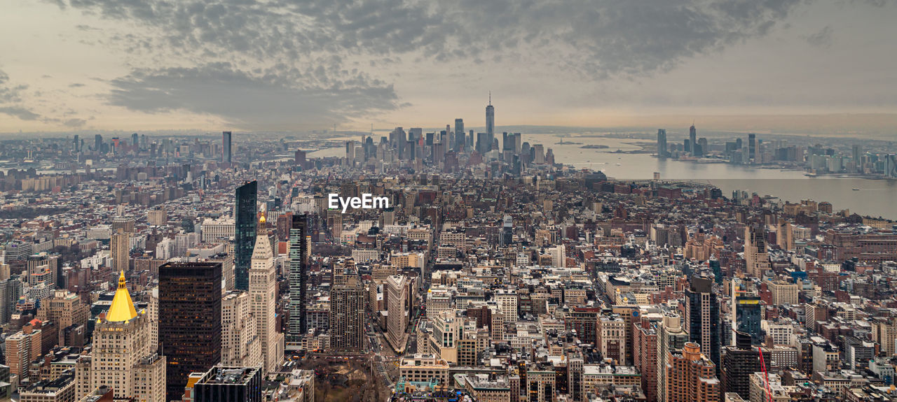 AERIAL VIEW OF MODERN BUILDINGS AGAINST CLOUDY SKY