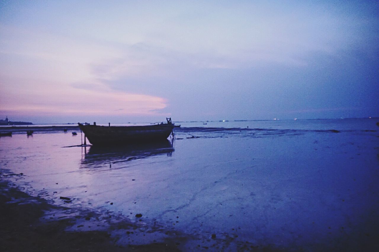 BOAT MOORED ON SHORE AGAINST SKY