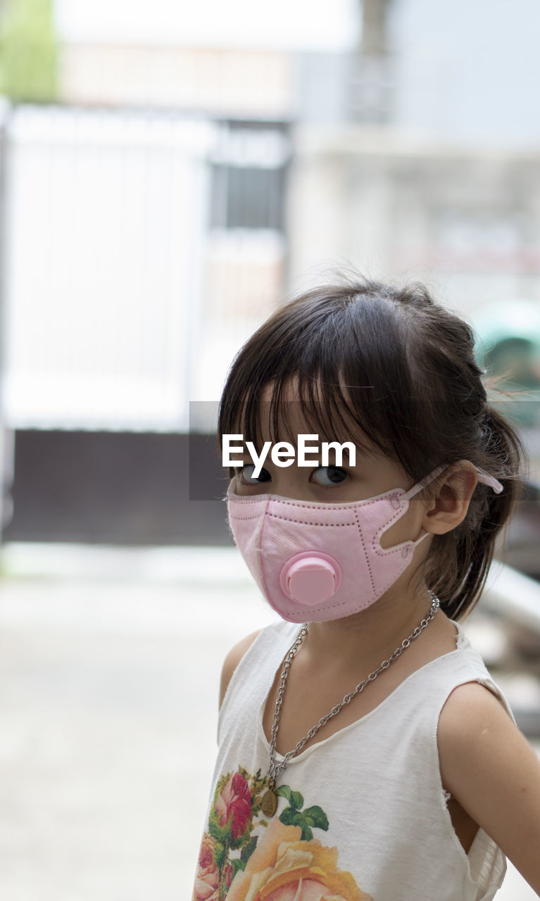 Portrait of cute girl wearing mask while standing outdoors