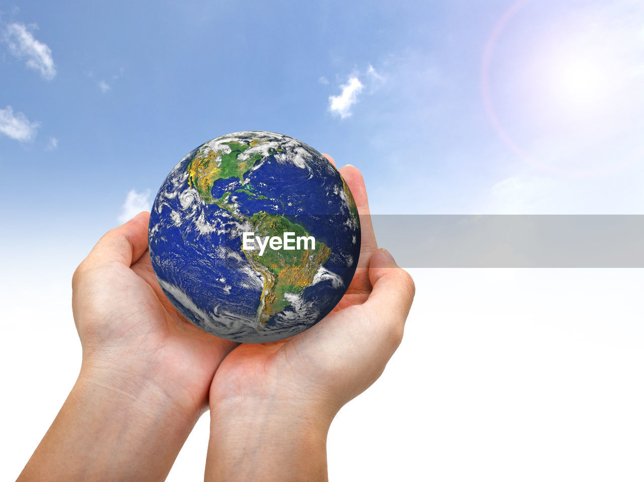 Close-up of hand holding planet earth against sky 