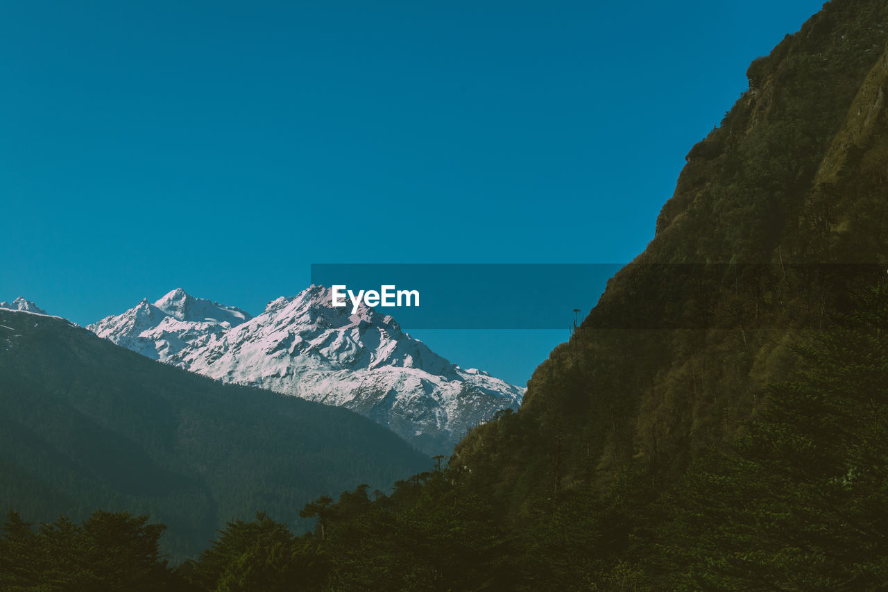 Scenic view of snowcapped mountains against clear blue sky