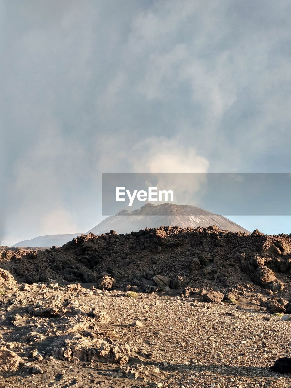 Smoke emitting from volcanic mountain against sky