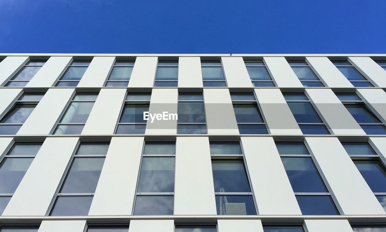 Low angle view of modern office building against clear blue sky