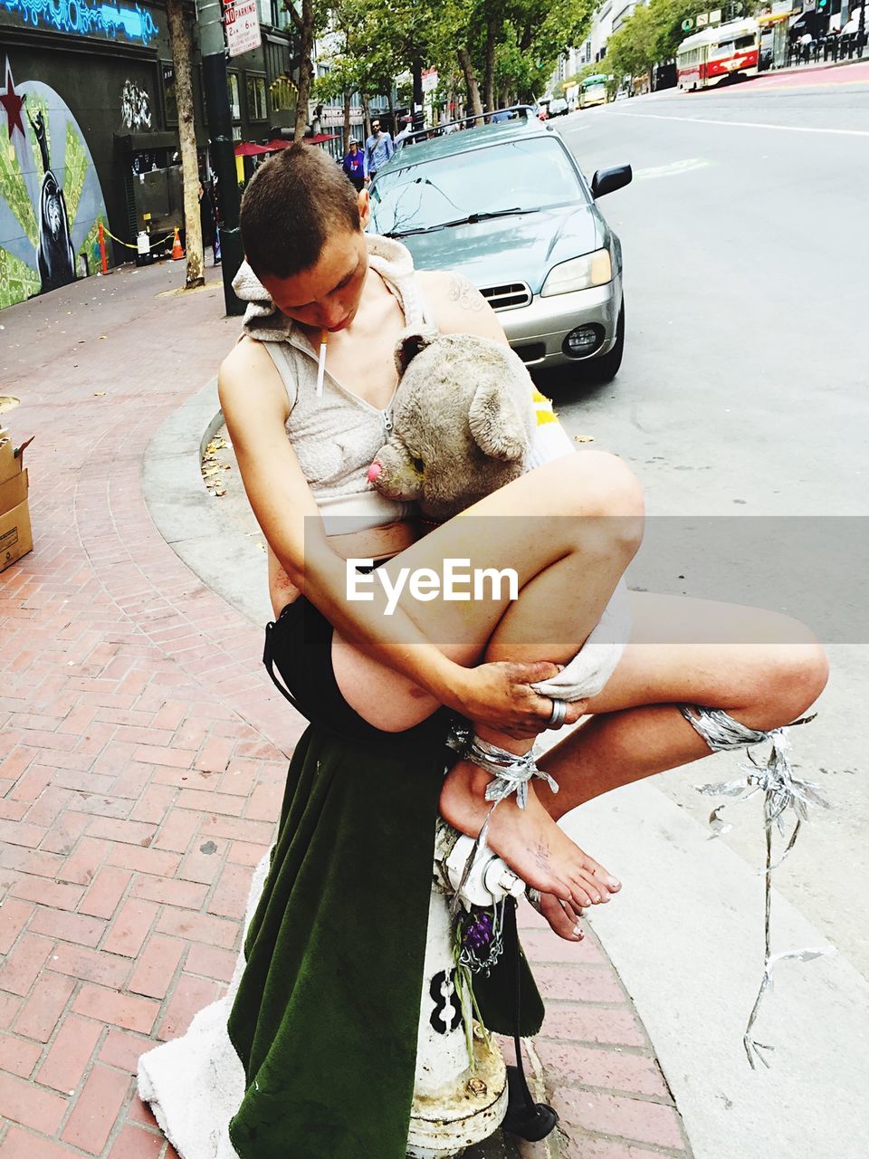 Woman sitting with stuffed toy on street