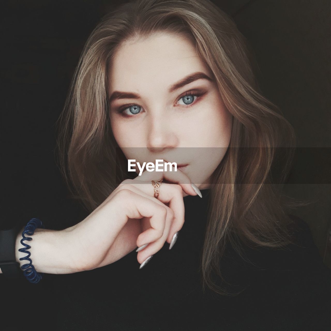 Close-up portrait of beautiful young woman against black background