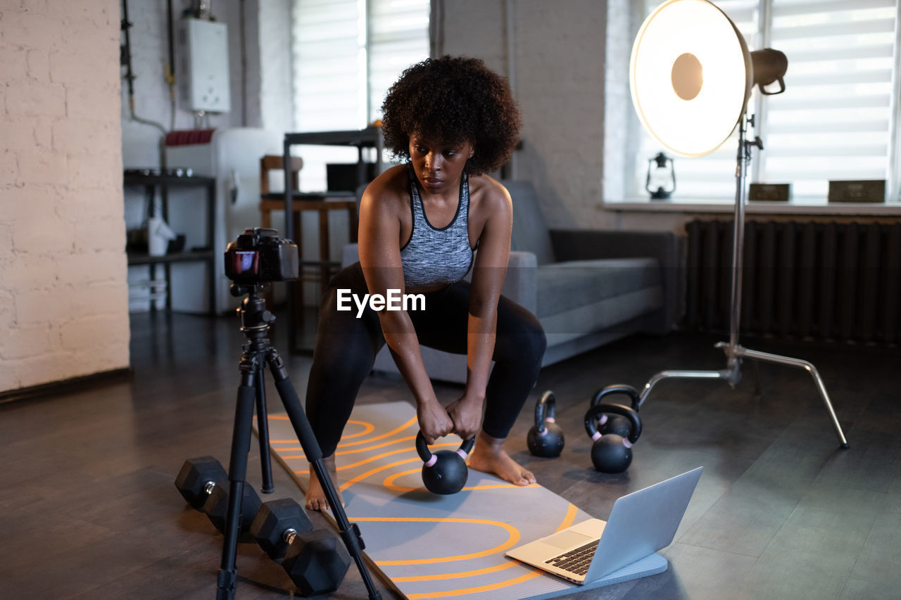 Ethnic sportswoman lifting kettlebell near camera