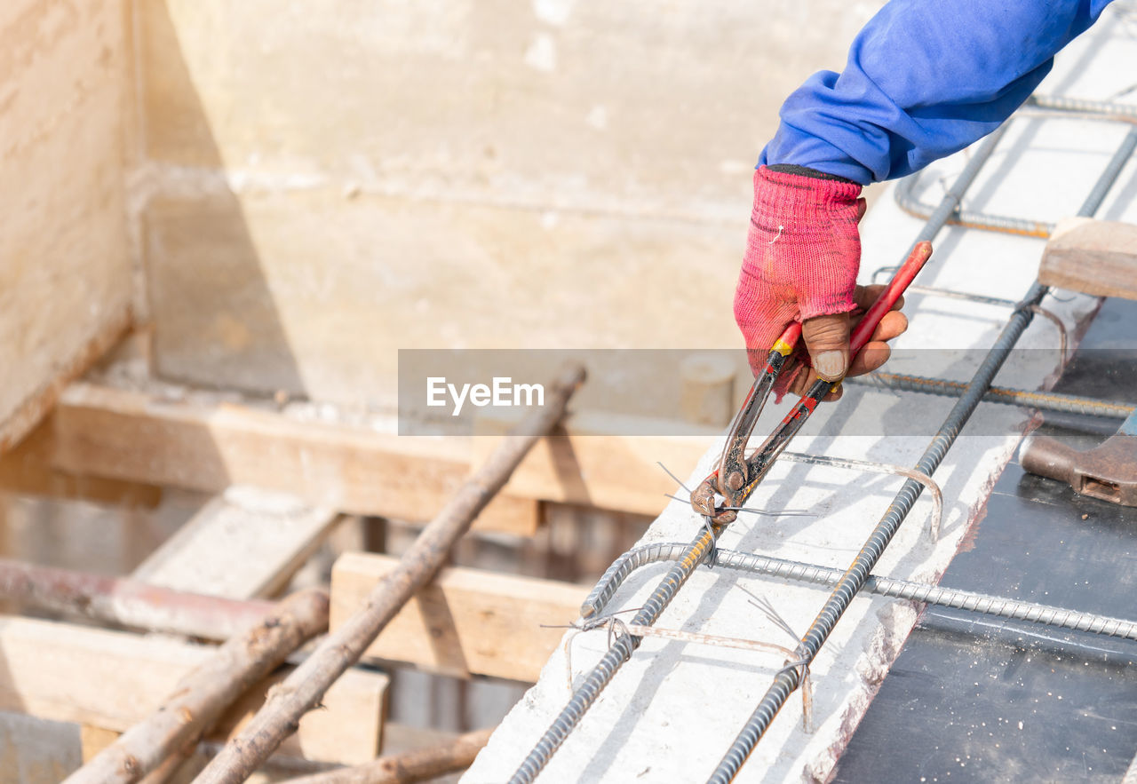 Woker holding pliers bundle wire steel rebar in construction site.