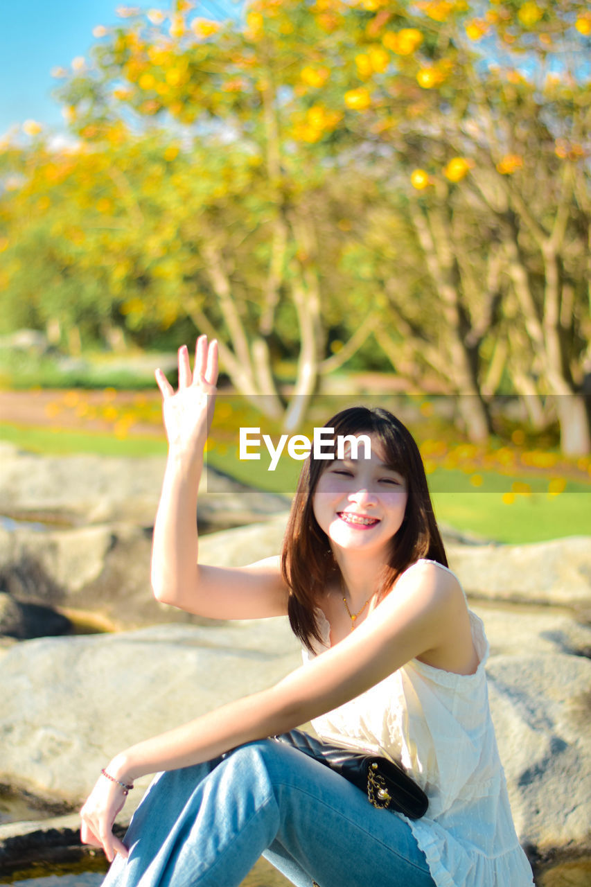 Portrait of young woman sitting on retaining wall