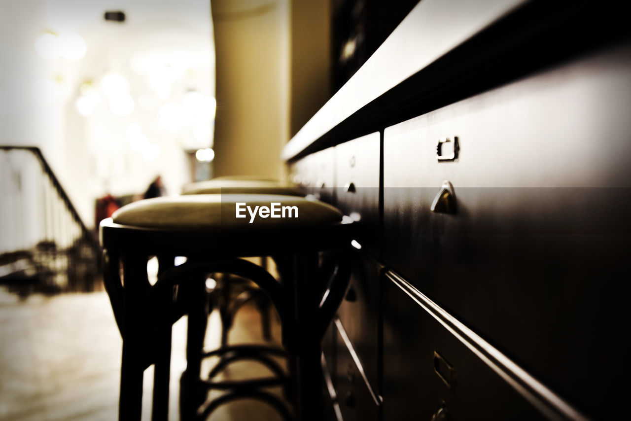 Close-up of stools by cabinet