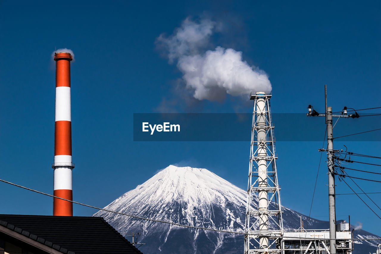 Industrial smokestack against view of mount fuji