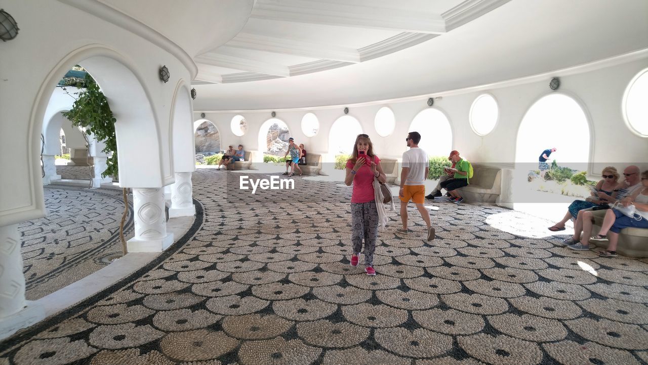 REAR VIEW OF PEOPLE WALKING ON TILED FLOOR