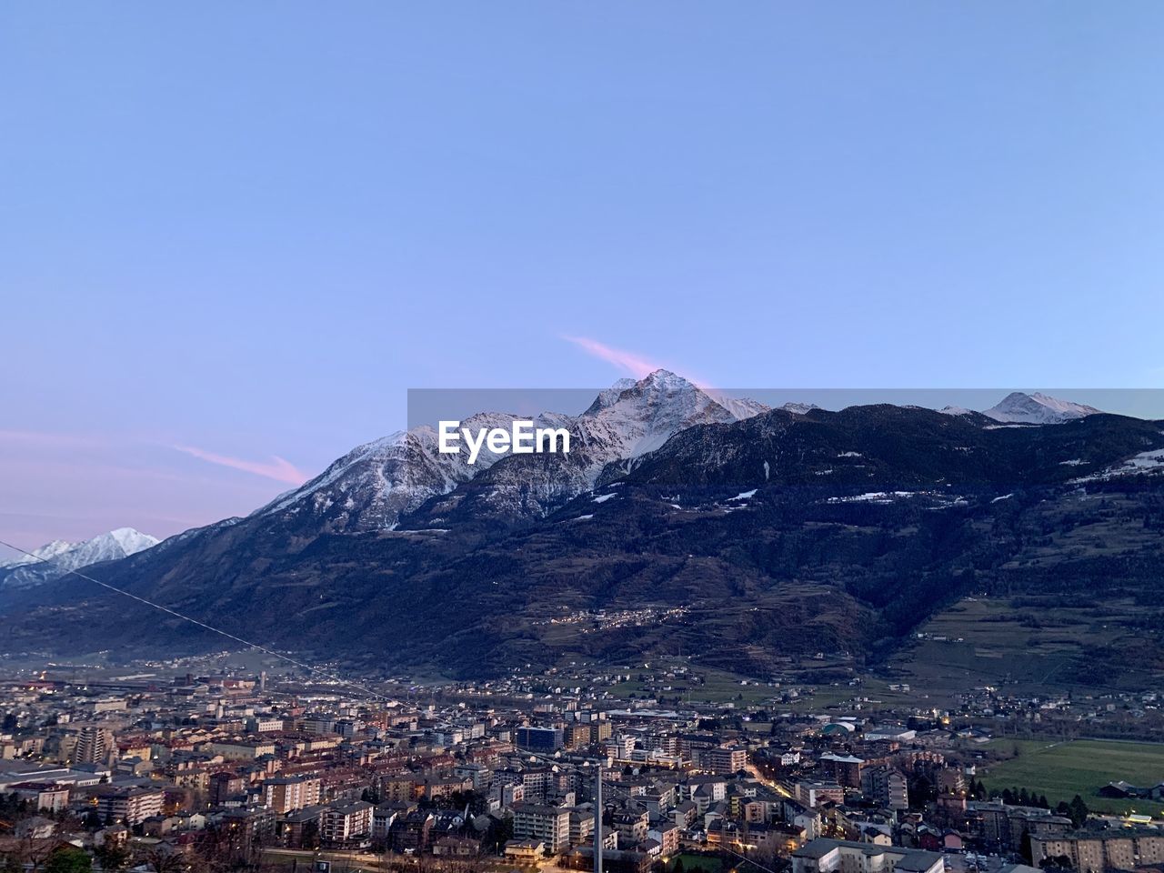 Aerial view of townscape by mountains against clear sky