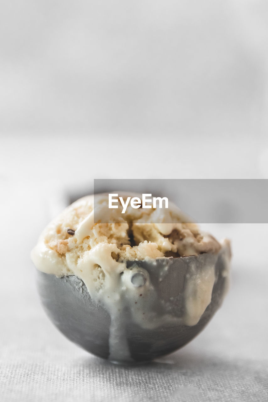 Close-up of ice cream in scooper against white background