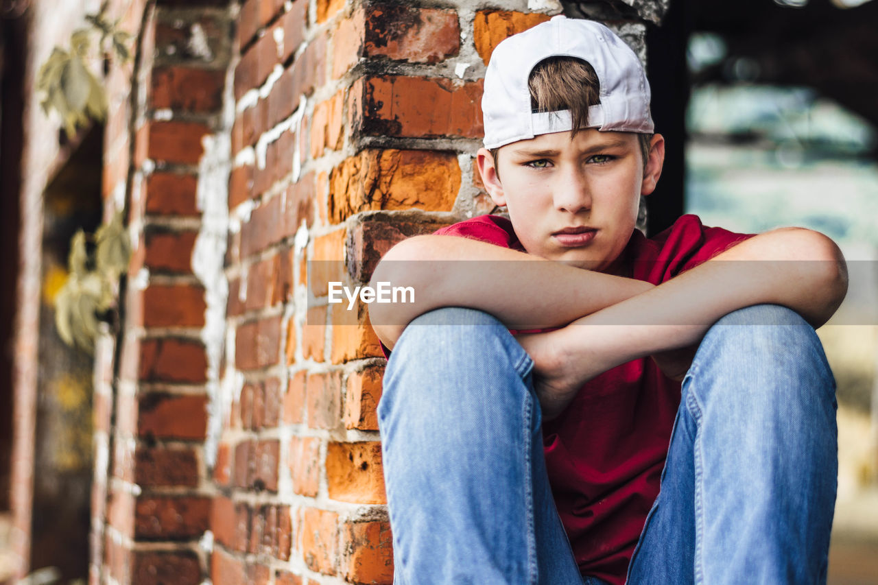 Portrait of a young man leaning against wall