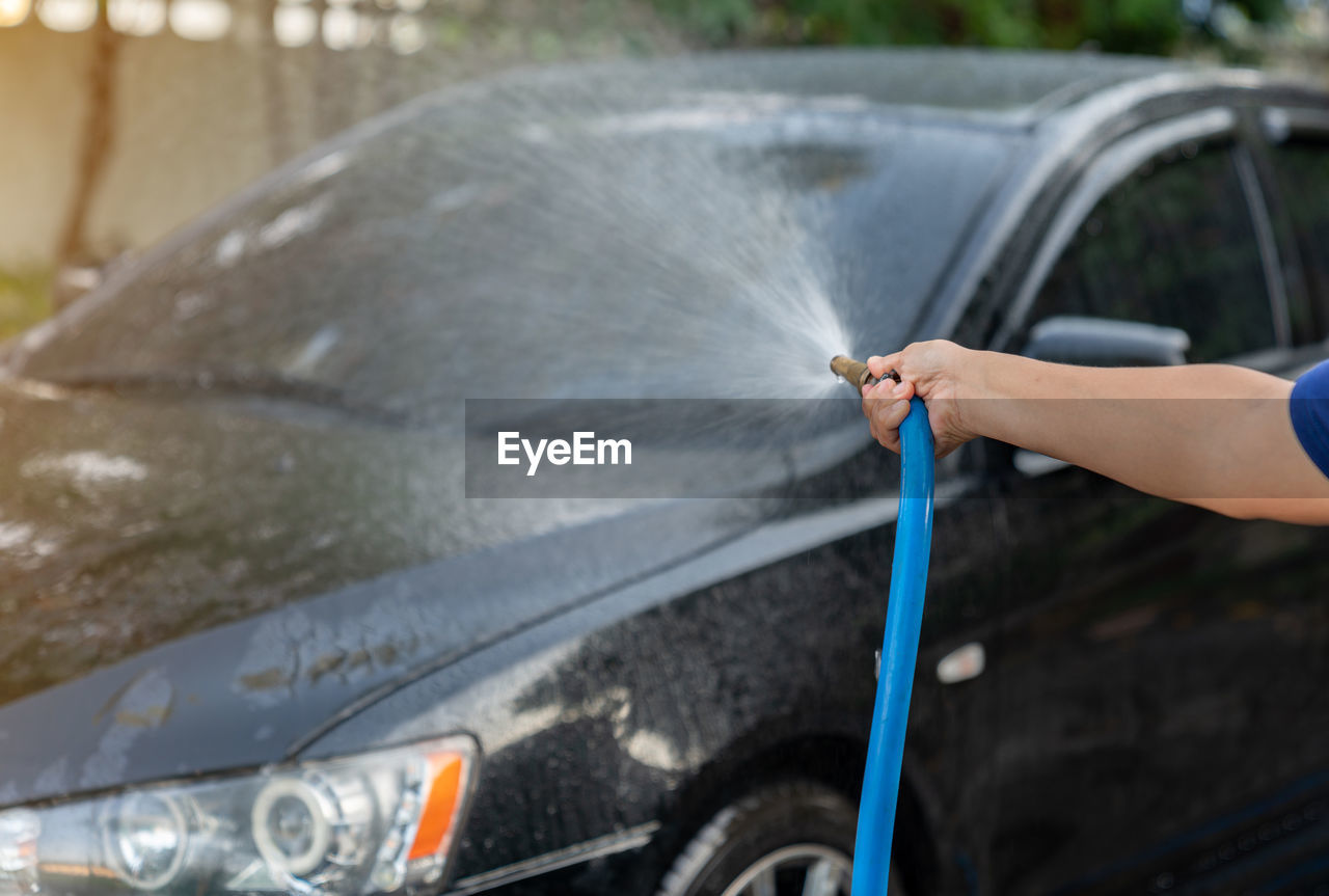 The man use pressor spray water car wash at home in a holiday.